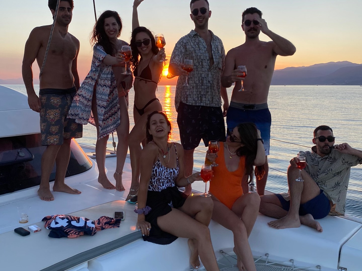 Group of people celebrating with drinks on a boat at sunset.