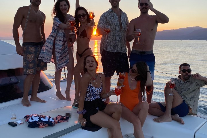 Group of people celebrating with drinks on a boat at sunset.