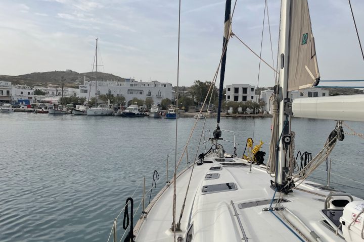 View from a sailboat deck towards a harbor with buildings and calm water.