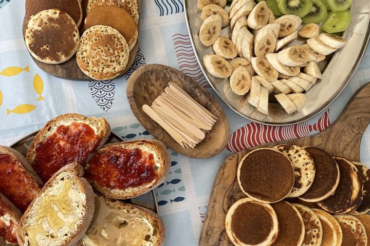 Assorted pancakes, toasts with spreads, and sliced fruits on a table.