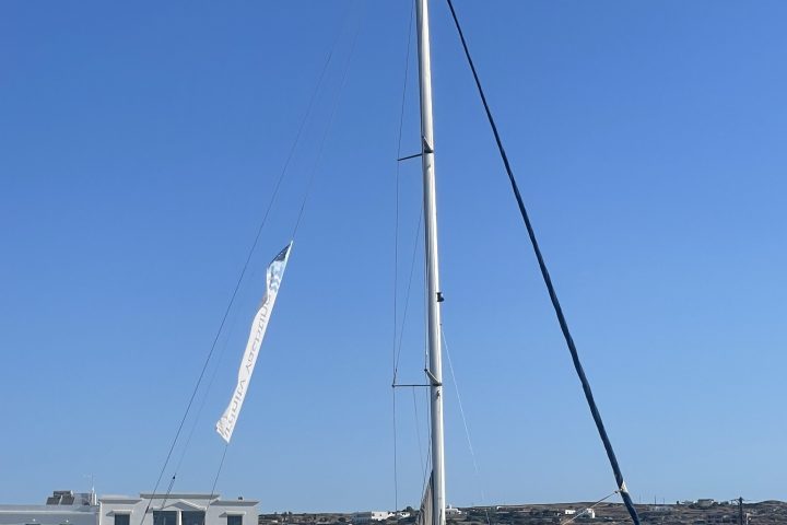 Sailboat docked near a white building under a clear blue sky.