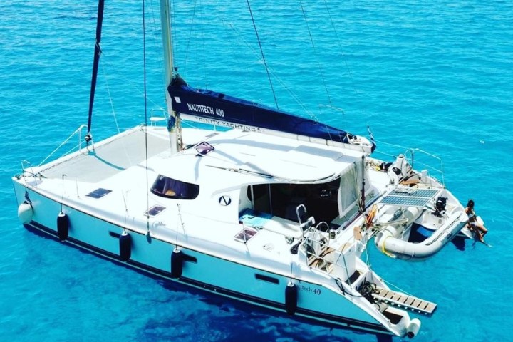 Catamaran named Nautitech 40 anchored in clear turquoise water.