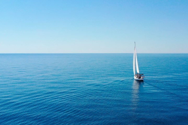 Sailboat on calm blue ocean under clear sky.